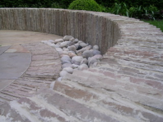 outdoor dining area circular seating garden patio stone wall laid on edge cobbles stone paving