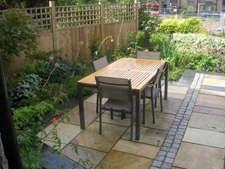 slate edging to paving patio outdoor dining ideas lush groundcover planting euphorbia brunnera stone setts timber fence