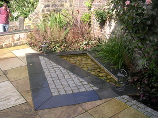 modern square pond with setts and slate paving cobbles triangle water feature stone paving contemporary garden design