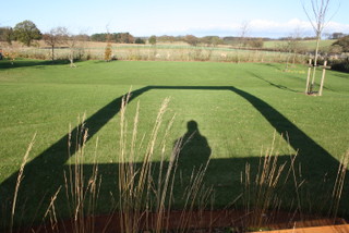 shadow of steel frame sculpture on garden lawn landscape design contemporary garden design