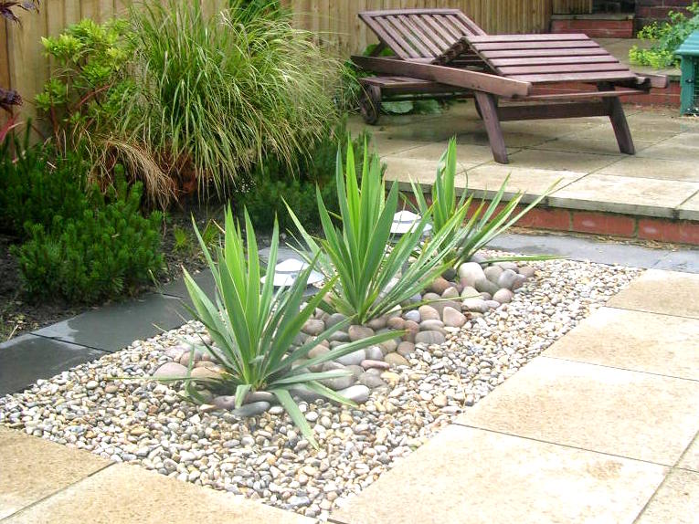 modern planting design cobbles stones and paving landscaping yucca phormium plants