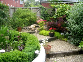 Leeds lush garden with gravel steps with timber edge pot plants and cobbles in a small garden