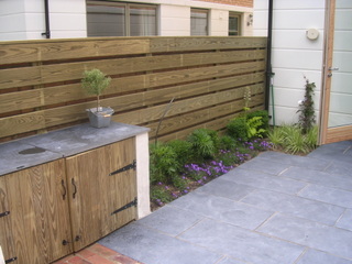 garden courtyard outdoor cupboard for dining and entertaining timber cupboard doors with slate worktop timber slat fencing dark paving in York