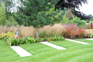 large stone paving steps through lawn bergenia and grasses planting contemporary garden design