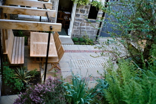 courtyard garden landscaping with built in seating and simple timber seat brick paving detail in stone paving and setts metal and timber simple pergola at Otley Yorkshire