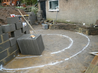 marking out for landscaping white spray paint on patio area garden construction paving slabs and breeze blocks