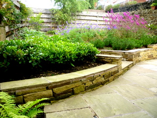 low stone retaining wall for planting stone paving patio sloping garden yorkshire