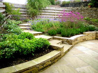 curved stone steps with low stone retaining wall up a yorkshire garden stone paving landscaping sloping garden