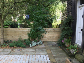setts and yorkshire sandstone paving in patio timber slatted fence for privacy